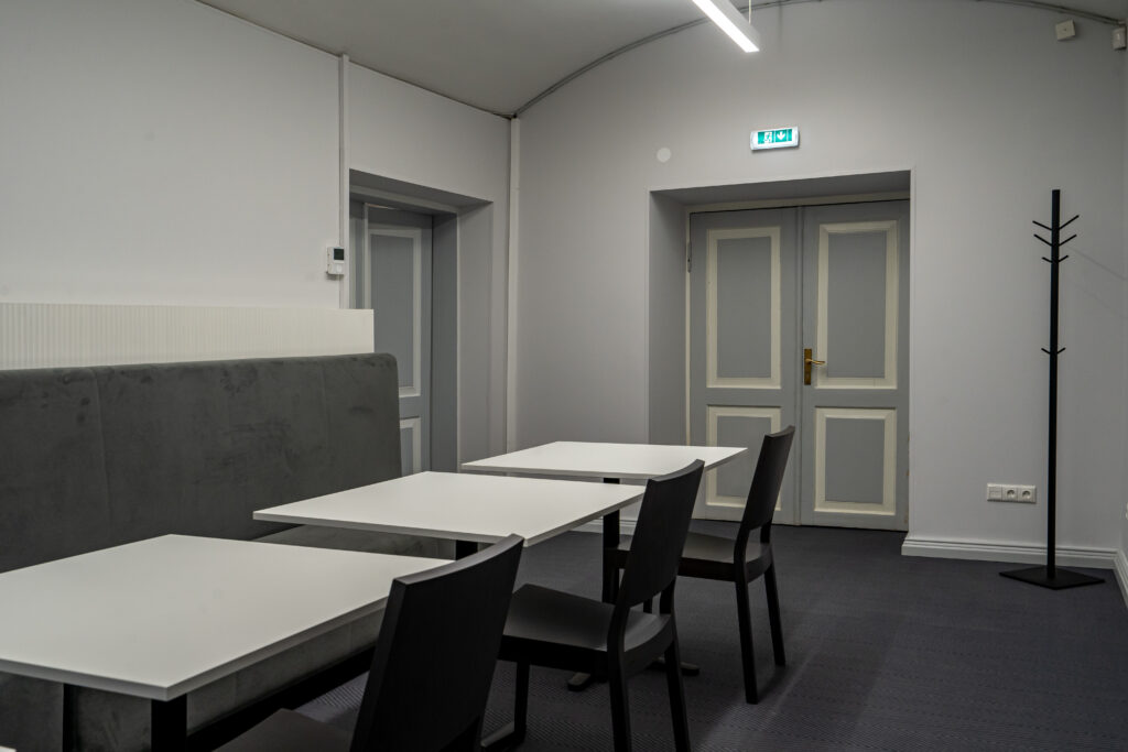 Hele puhkeruum valgete laudade ja hallide toolidega