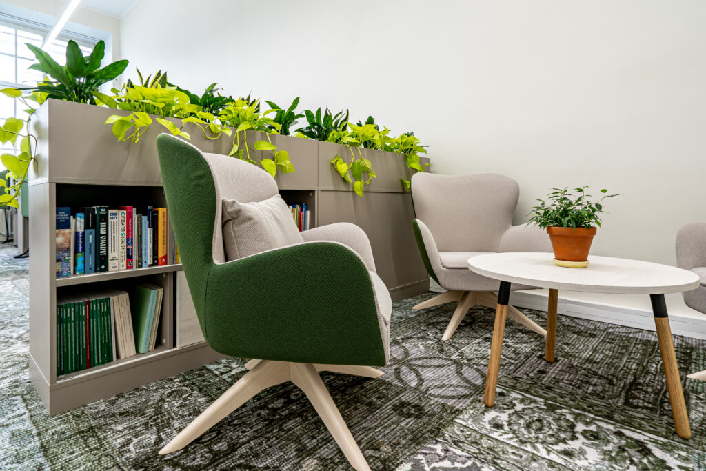 Puhkenurk koos kahe tugitooli, väikese laua ja taimerikkal riiulil olevate raamatutega